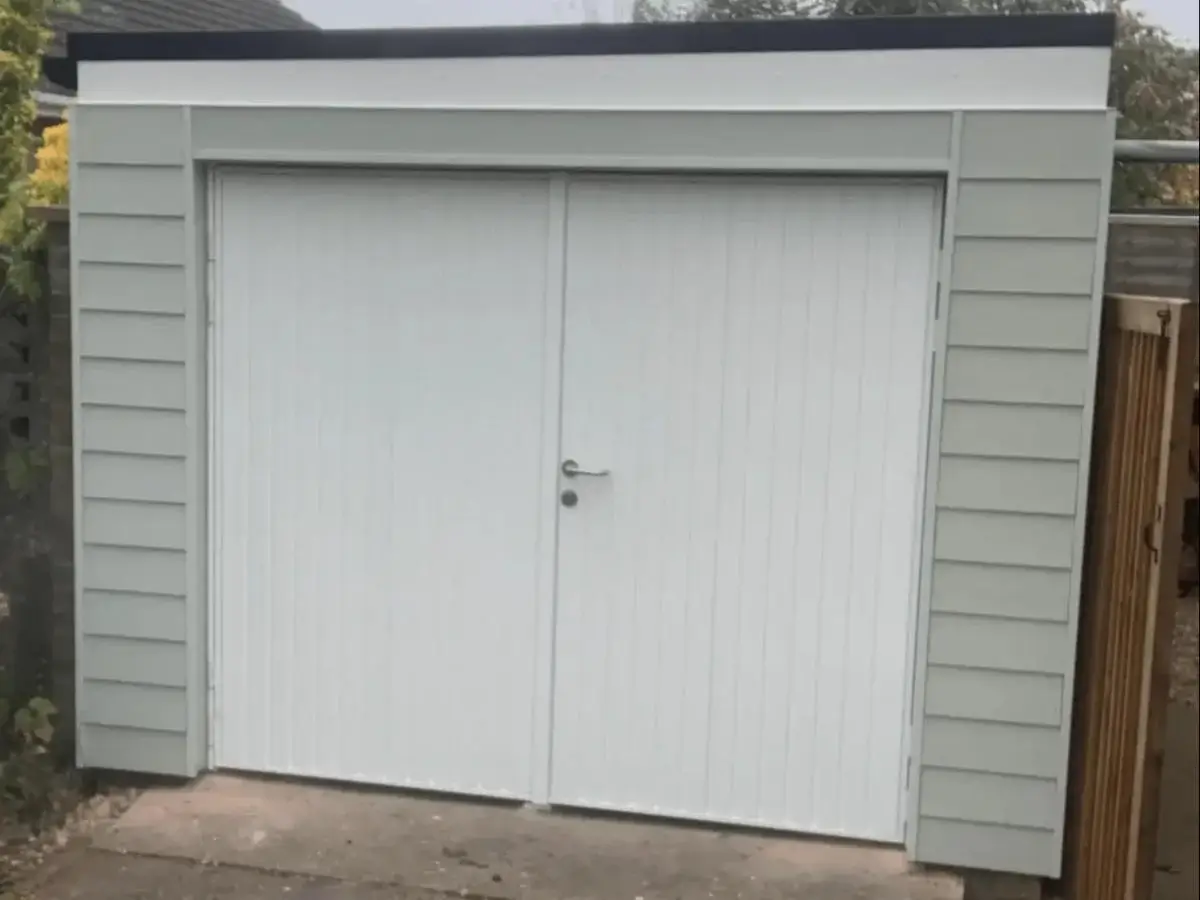 Light grey horizontal cladding fitted around white side-hinged double garage doors. By Norfolk Exterior Solutions.